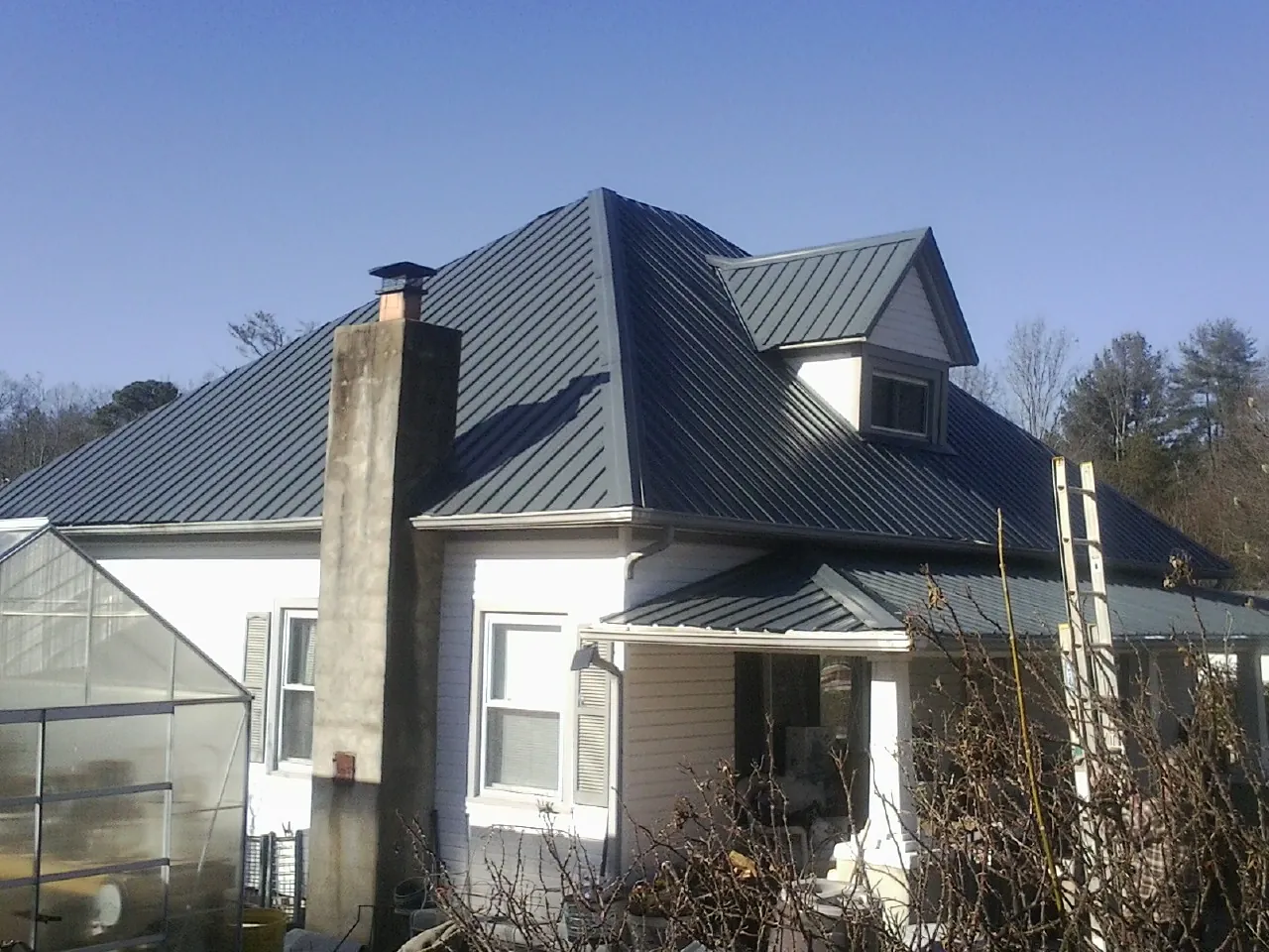 Dark blue standing seam metal roof on a white farmhouse with dormer — Slate & Tile Roof Repair by Roofing Brothers in Trumbull