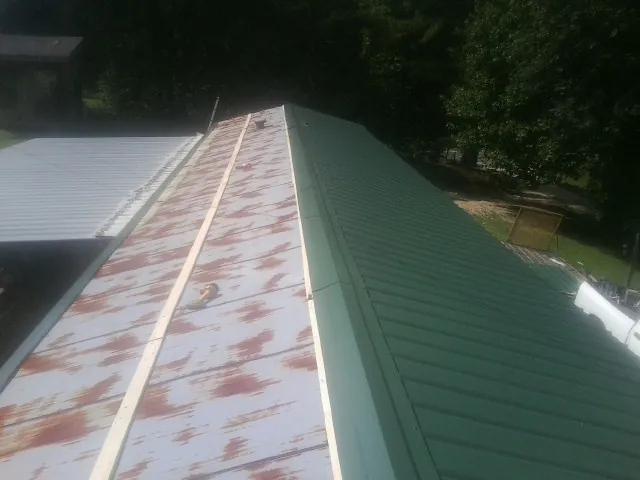 Old rusted panels beside newly installed green metal roofing — Wind Damage Roof Repair by Roofing Brothers in Trumbull