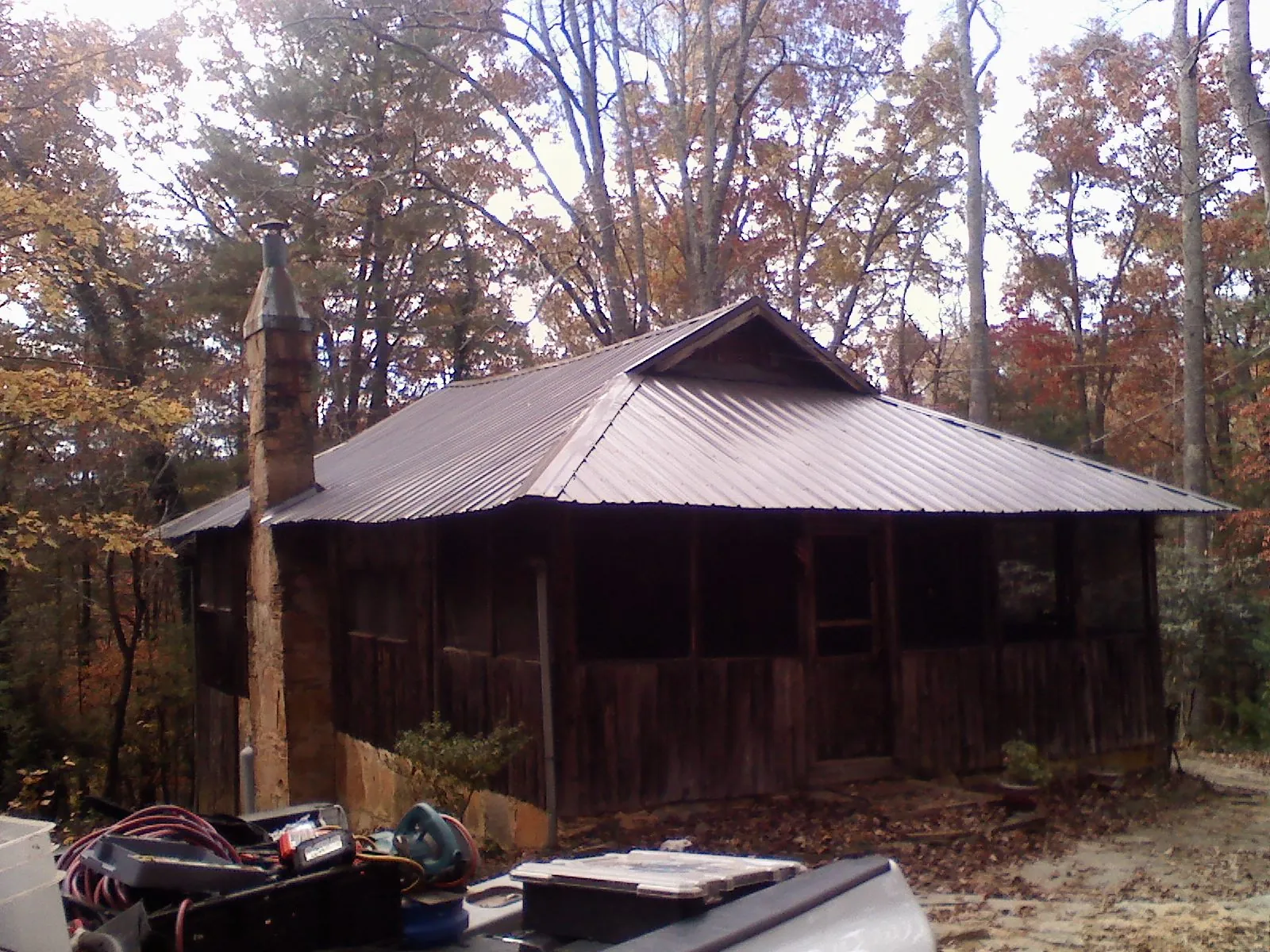 Brown metal hip roof on an old cabin with a stone chimney in Trumbull